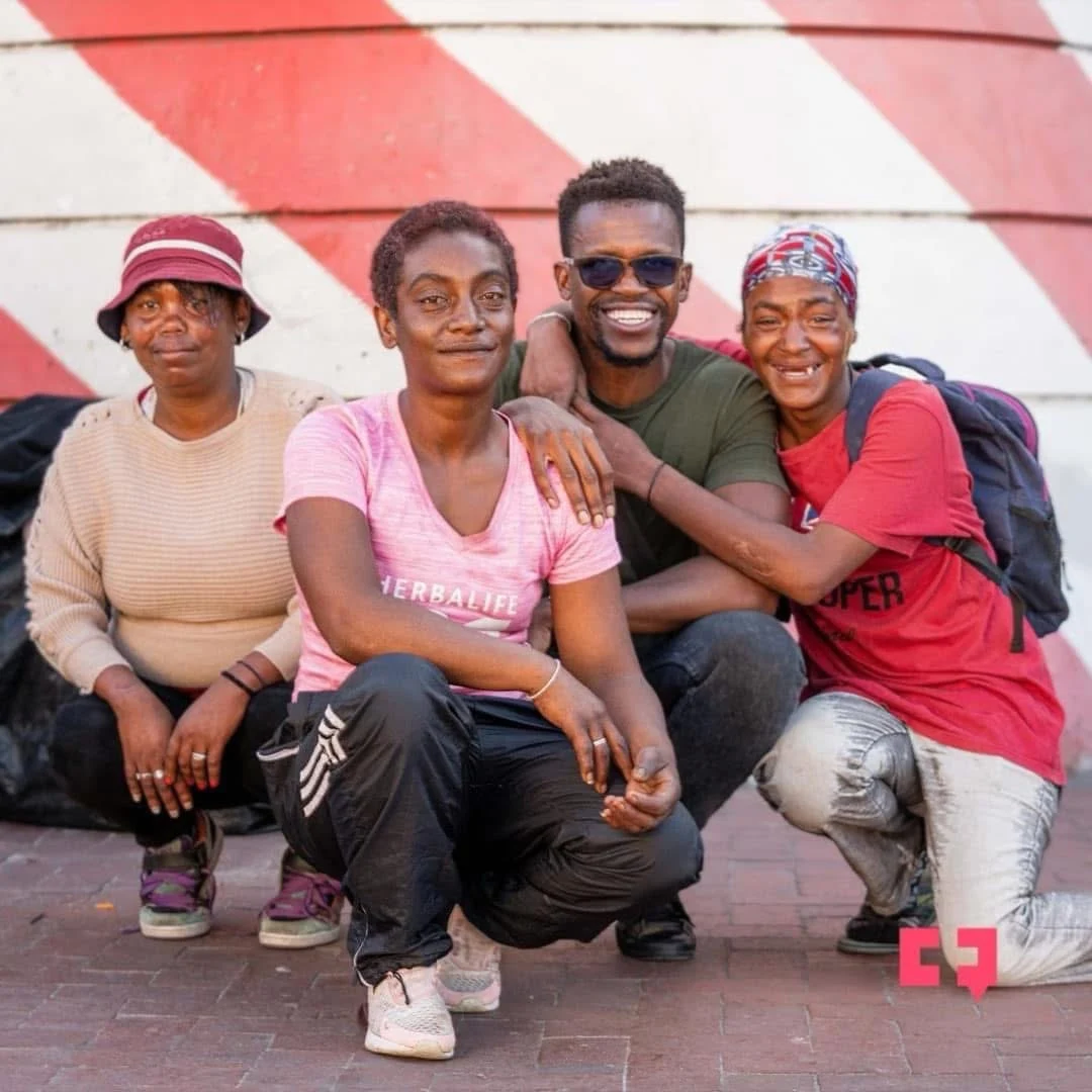 Phinius smiling with three companions outdoors.