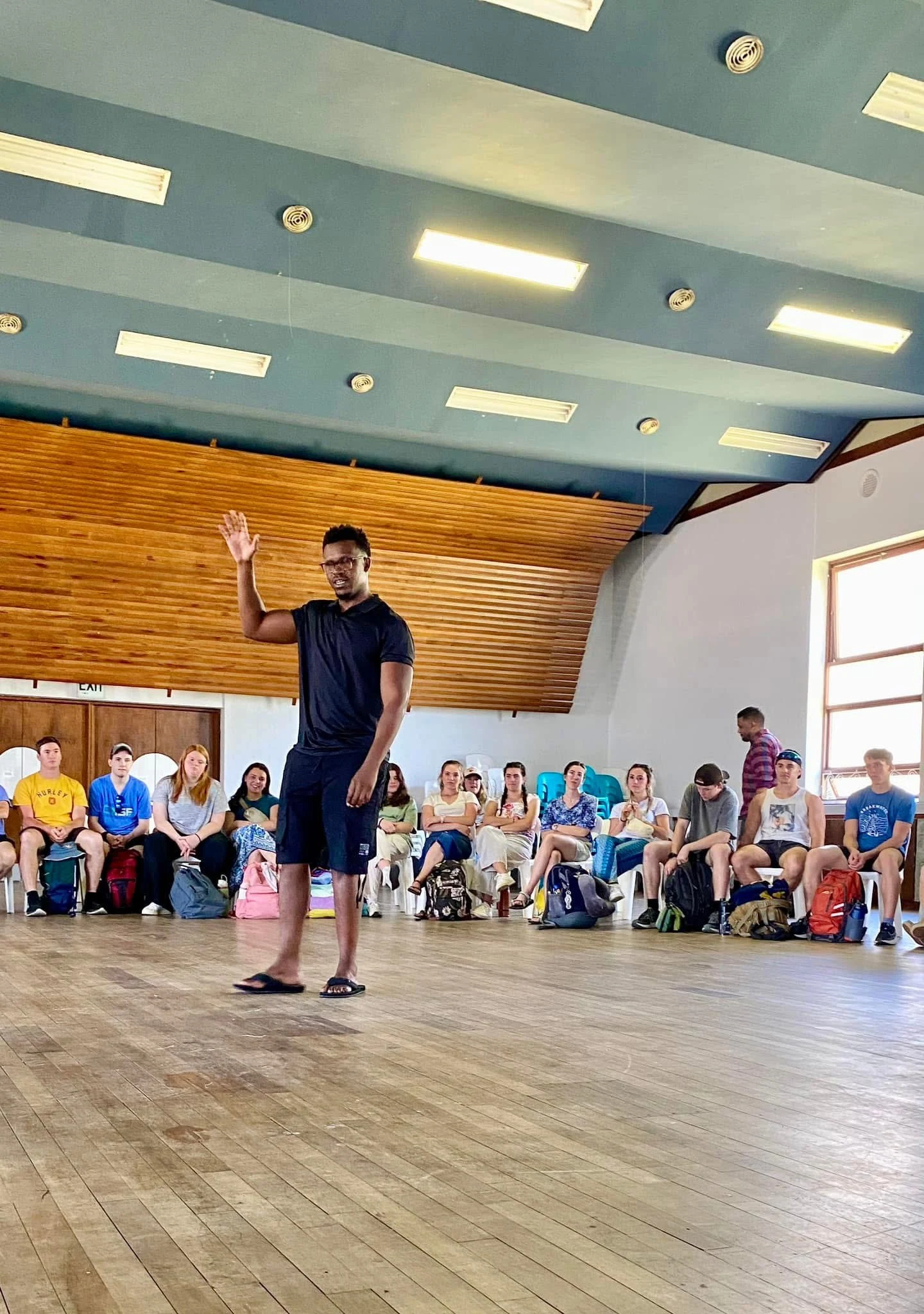 Phinius addressing a seated group in a community hall.