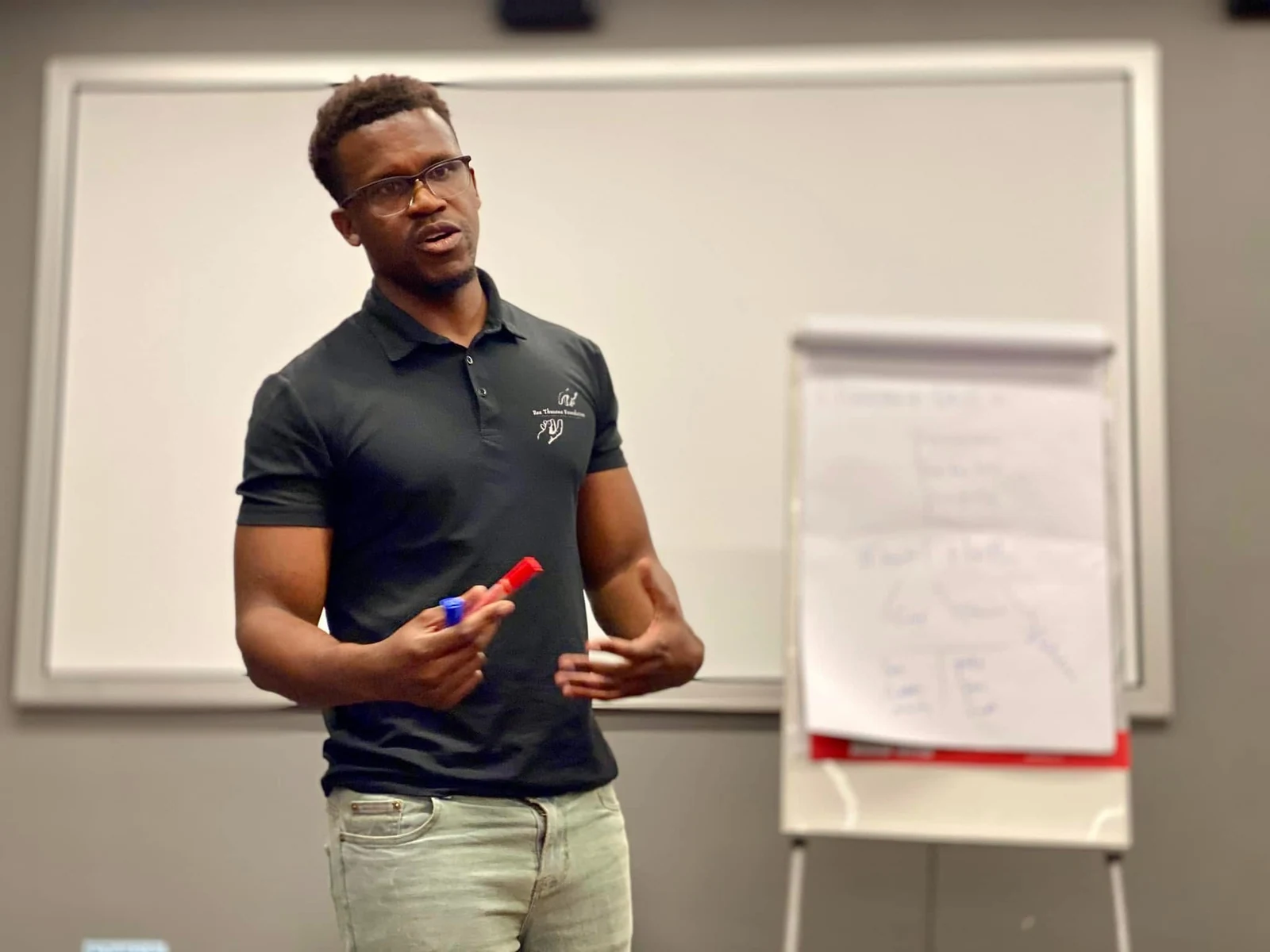 Phinius speaking beside a flip chart during a training session.