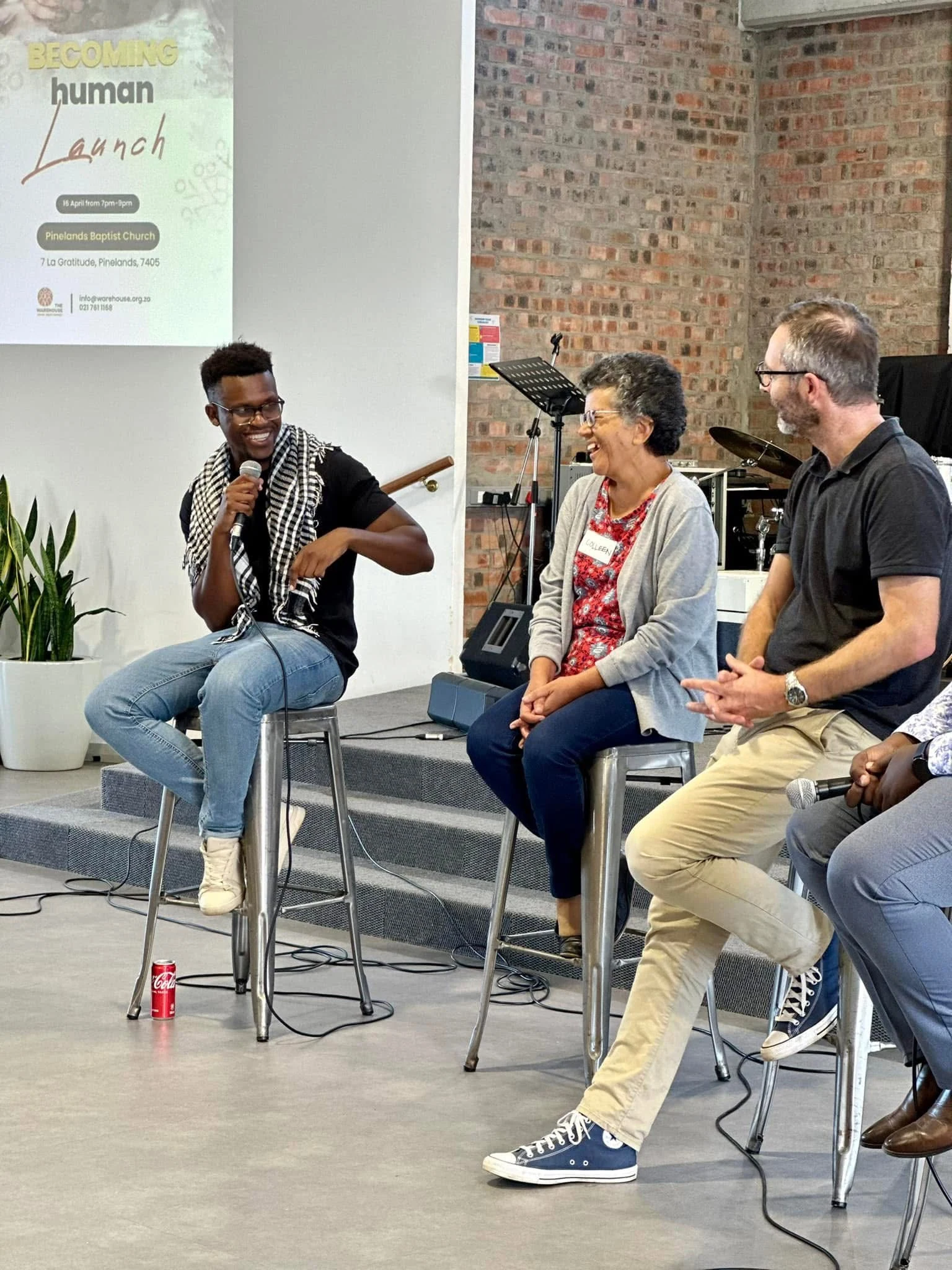 Phinius speaking alongside two other participants in a panel conversation.