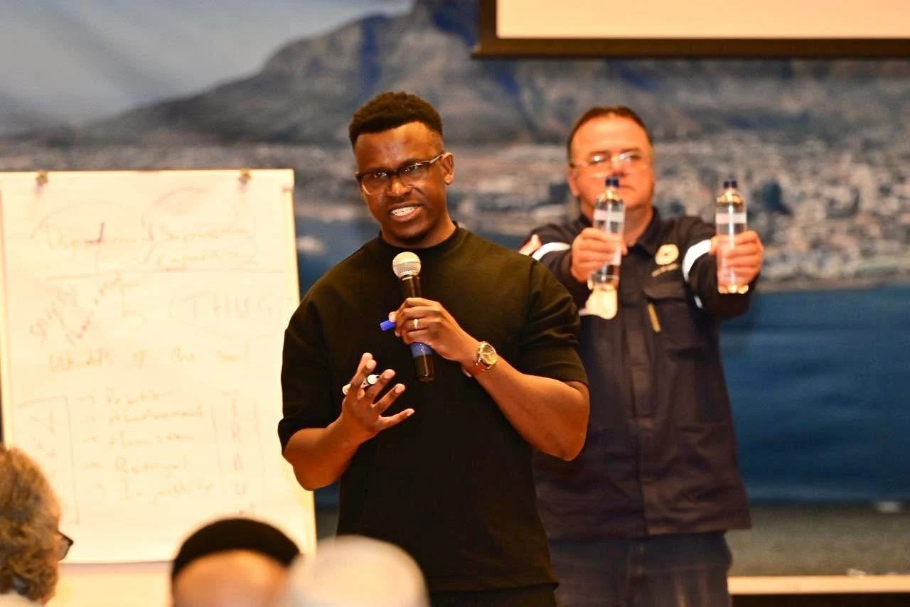 Phinius speaking with a handheld microphone at a gathering.