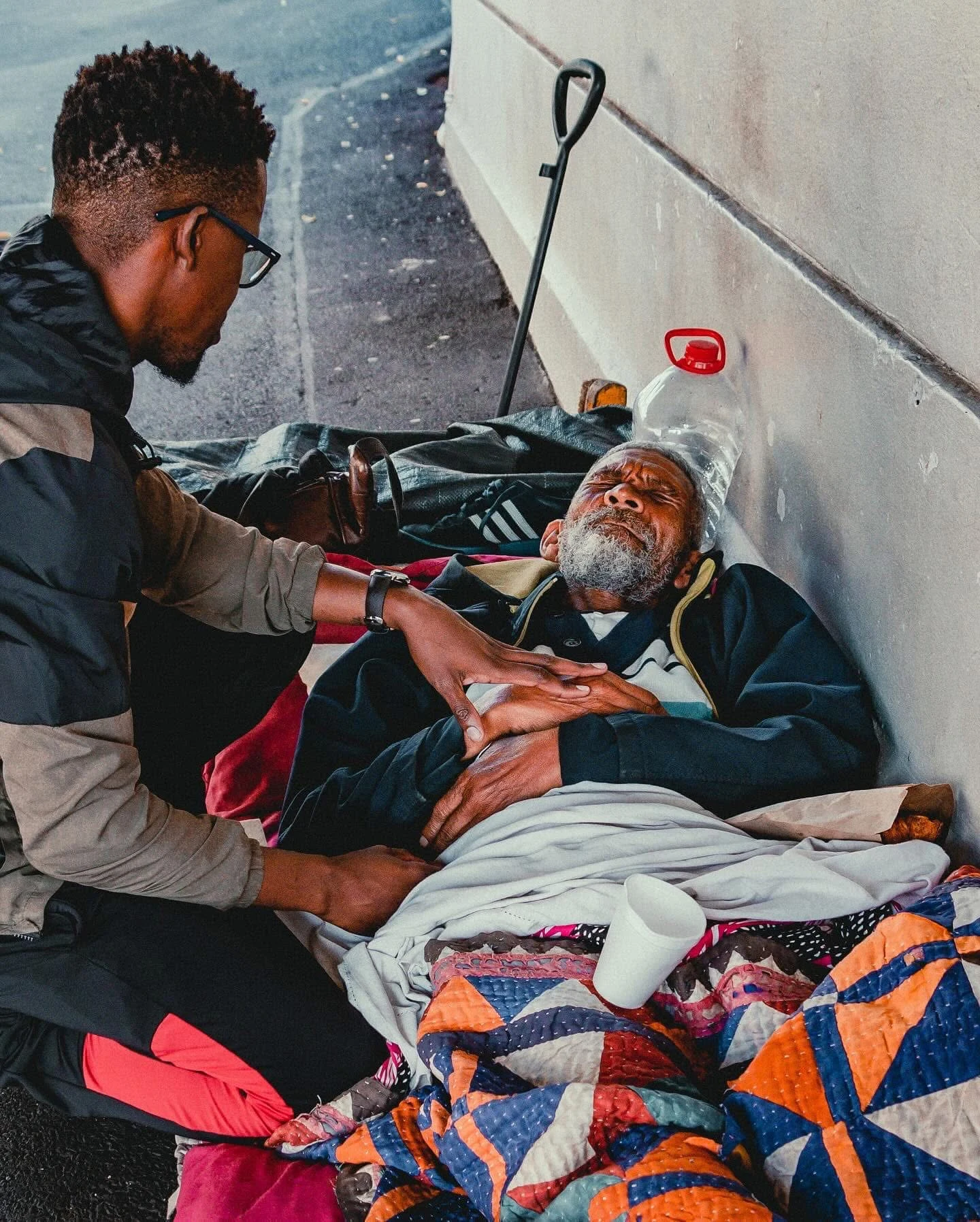 Phinius listening to a man resting beside his belongings during street engagement.
